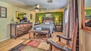 Ein Schlafzimmer mit Bett, Schminktisch, Bank und Deckenventilator.