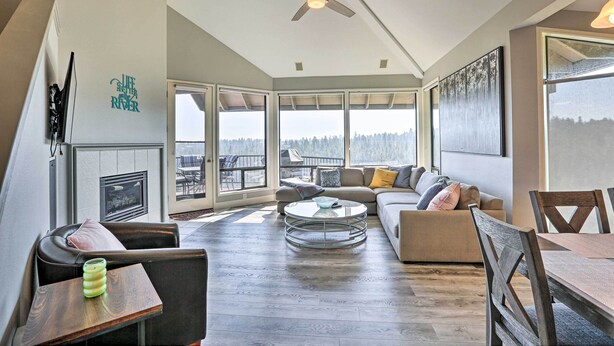 A spacious living room with a large window, a ceiling fan, and a fireplace.
