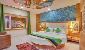 Una habitación de hotel moderna con una cama grande, almohadas verdes y púrpuras, un cabecero de madera y un panel decorativo en la pared.