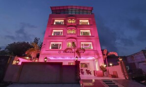 Un edificio de varios pisos con un letrero que dice "Tropical Roots".