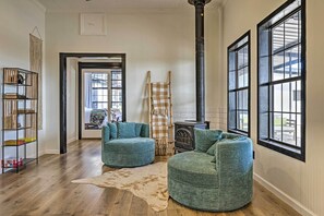 A cozy living room with a large window, a fireplace, and a rustic rug.
