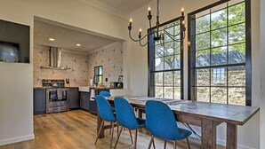 Una cucina moderna con zona pranzo, caratterizzata da una grande finestra, pavimento in legno e sedie blu.