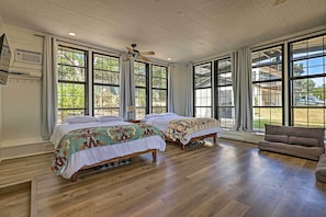 A spacious bedroom with two beds, large windows, and a ceiling fan.