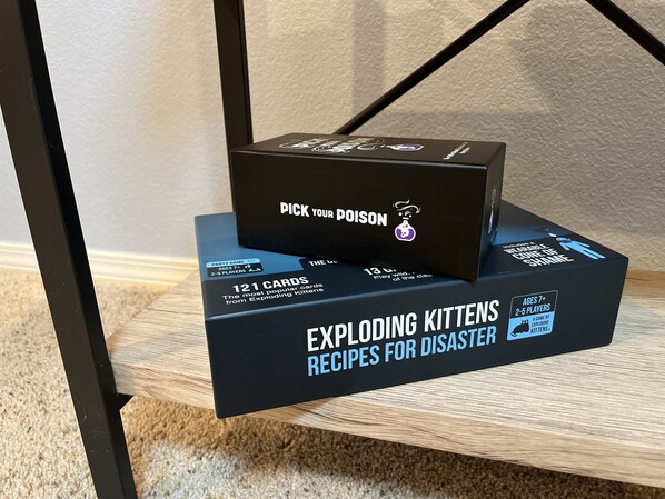 A game box labeled "EXPLODING KITTENS RECIPE FOR DISASTER" on a wooden surface.