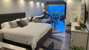 Camera d'albergo moderna con un grande letto, una scrivania, una sedia, un balcone con vista e una ventola a soffitto.