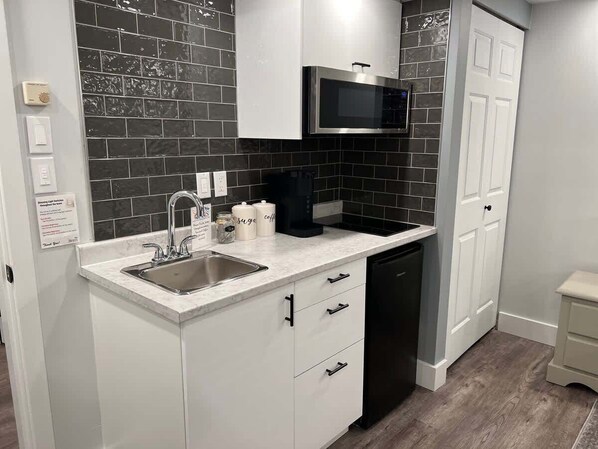 A kitchen with a sink, microwave, cabinets, and a dishwasher.