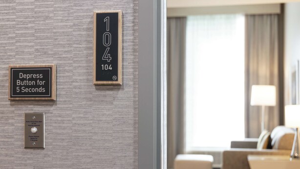 Habitación de hotel con cartel de número, botón de llamada y timbre.