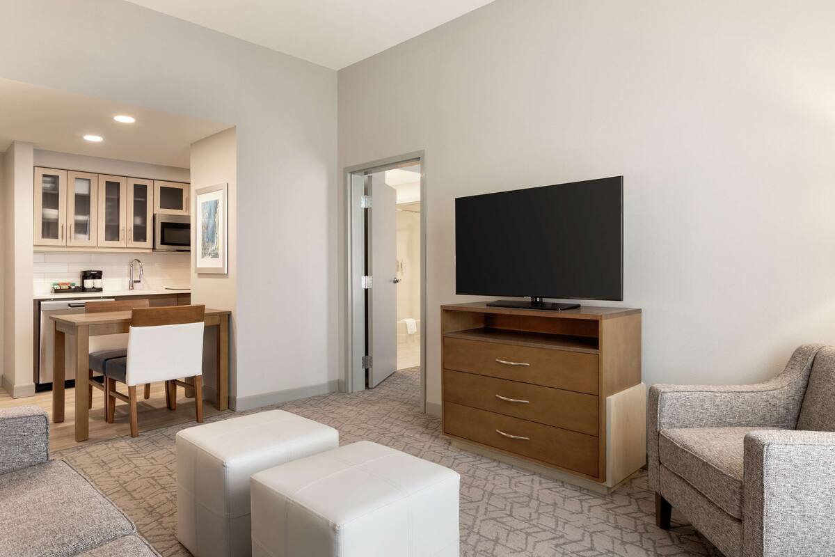 Una sala de estar moderna con un televisor de pantalla plana, un mueble de madera, un sofá y un comedor con una mesa y sillas.