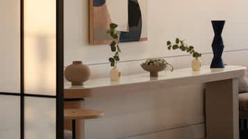 A modern interior with a minimalist design, featuring a long, low-profile table with decorative vases and a potted plant.