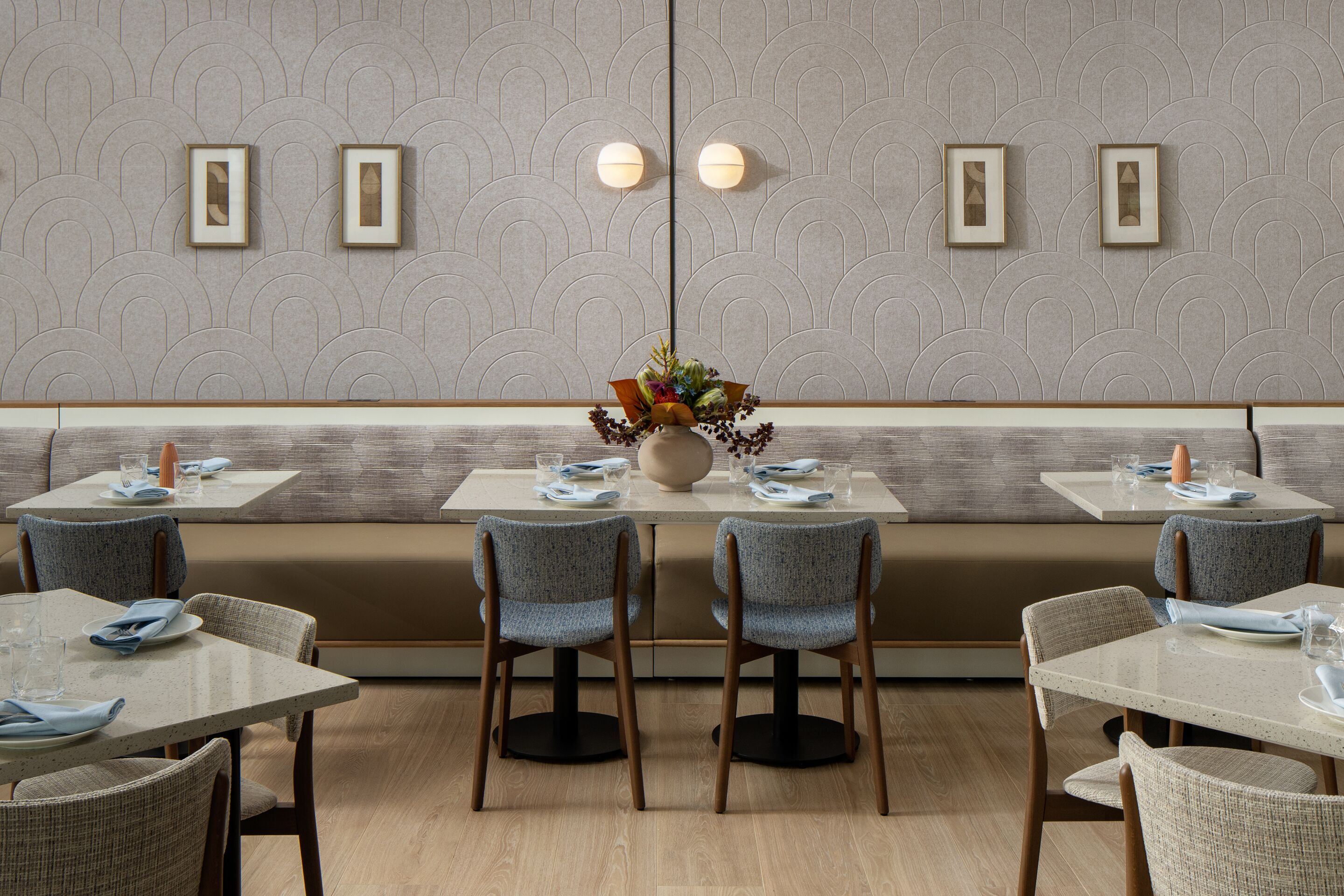 Un ristorante dall'arredamento moderno, con un'area salotto centrale caratterizzata da una panca bassa e due tavoli con sedie.