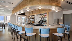 A modern bar area with a curved counter, bar stools, and a variety of bottles and glasses. - Hotel Marcel New Haven, Tapestry Collection By Hilton (New Haven)