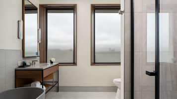 Een moderne badkamer met een vrijstaand bad, een wastafel met spiegel en een toilet.