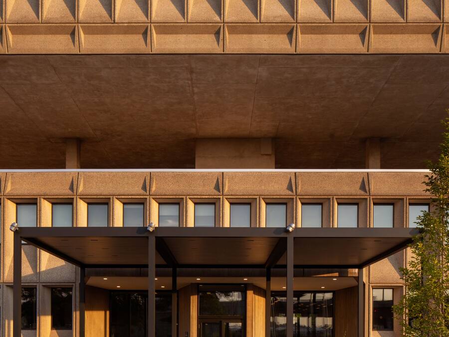 Un bâtiment moderne doté d’une façade géométrique, de grandes fenêtres et d’un espace d’entrée abrité.