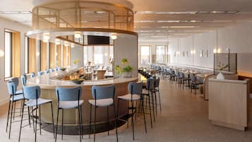 A modern hotel lobby with a central bar area, seating arrangements, and a reception desk.