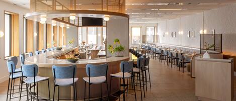 Eine moderne Hotelhalle mit Bar im Zentrum, Sitzgelegenheiten und einer Rezeption.