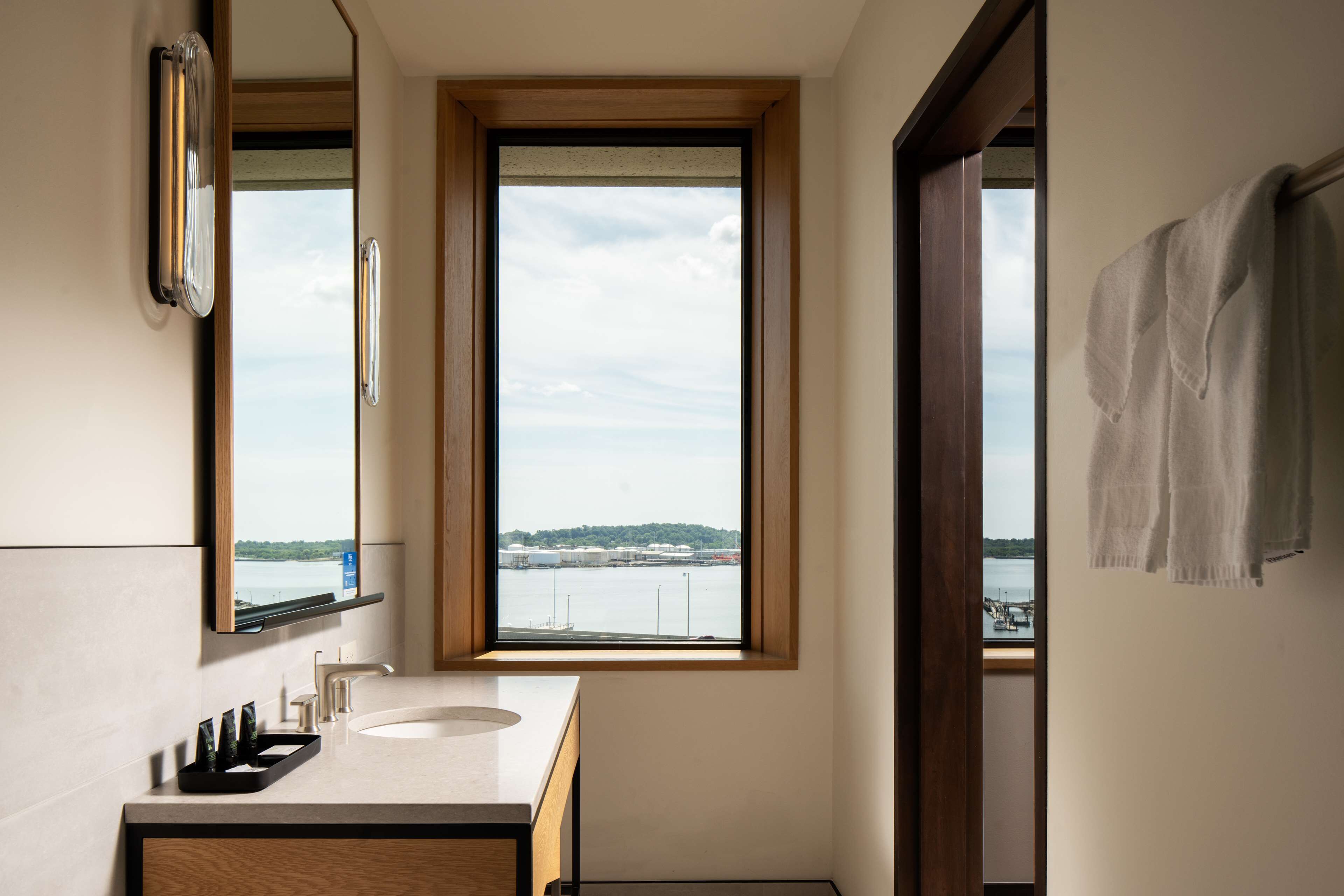 A bathroom with a large window, a sink, and a mirror.