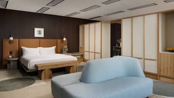 A modern hotel room with a bed, a sofa, a bedside table, and a sliding shoji screen.