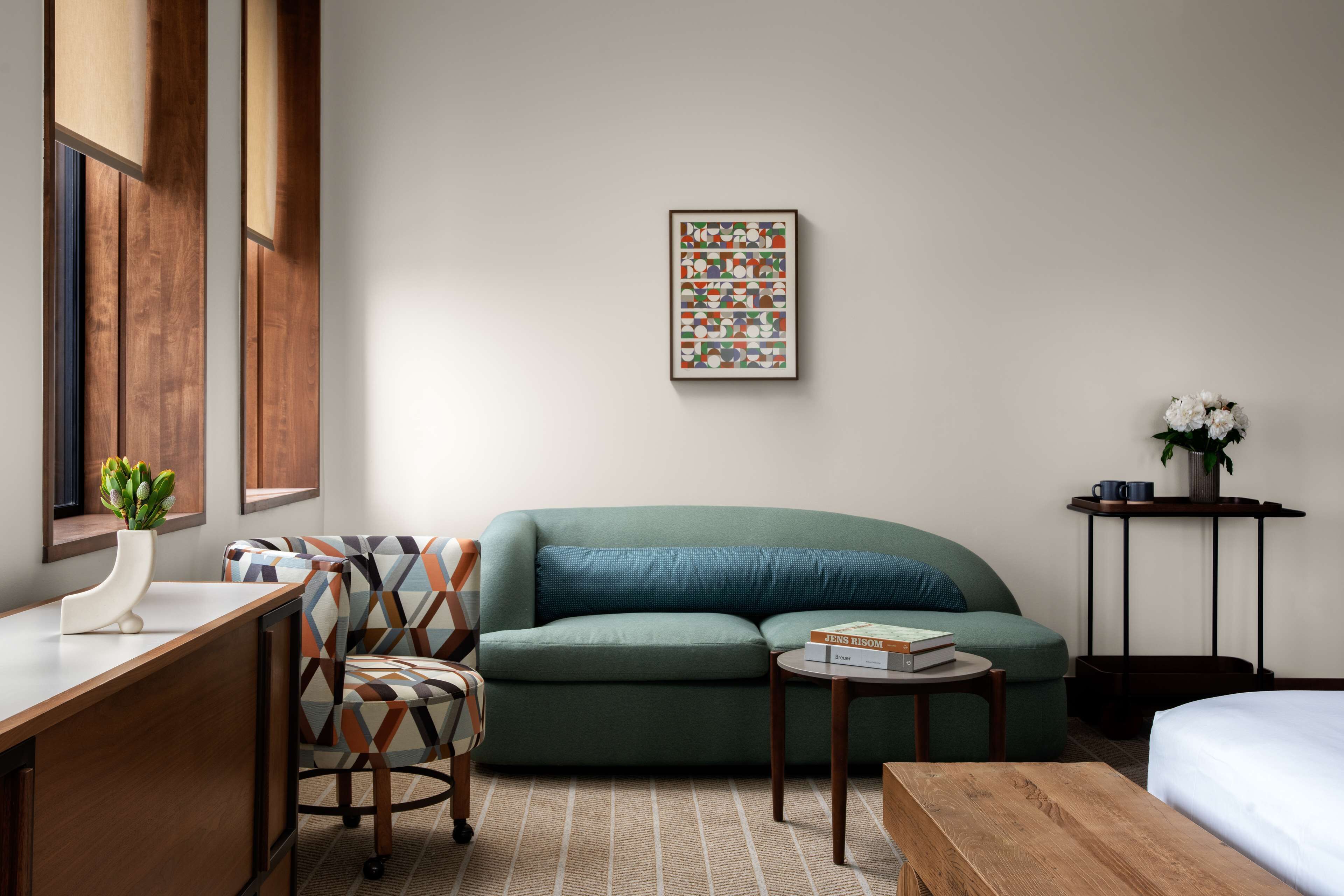 Una habitación moderna con un sofá verde, un escritorio de madera y un cuadro abstracto enmarcado en la pared.