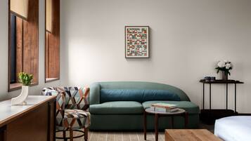 A modern room with a green sofa, a wooden desk, and a framed abstract painting on the wall.