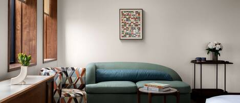 A modern room with a green sofa, a wooden desk, and a framed abstract painting on the wall.