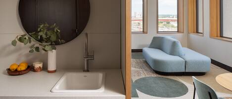 A modern kitchen with a round mirror, a sink, and a bowl of fruit.