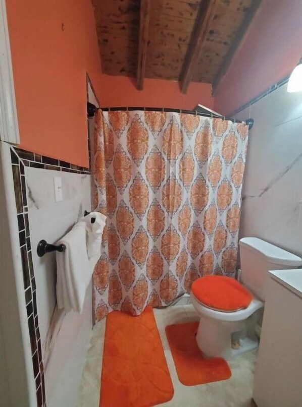 A bathroom with a shower curtain, a toilet, and a towel rack. - Maryville Studio (St.Thomas)
