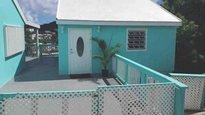 A turquoise building with a white door and window, surrounded by a white fence. - Maryville Studio (St.Thomas)