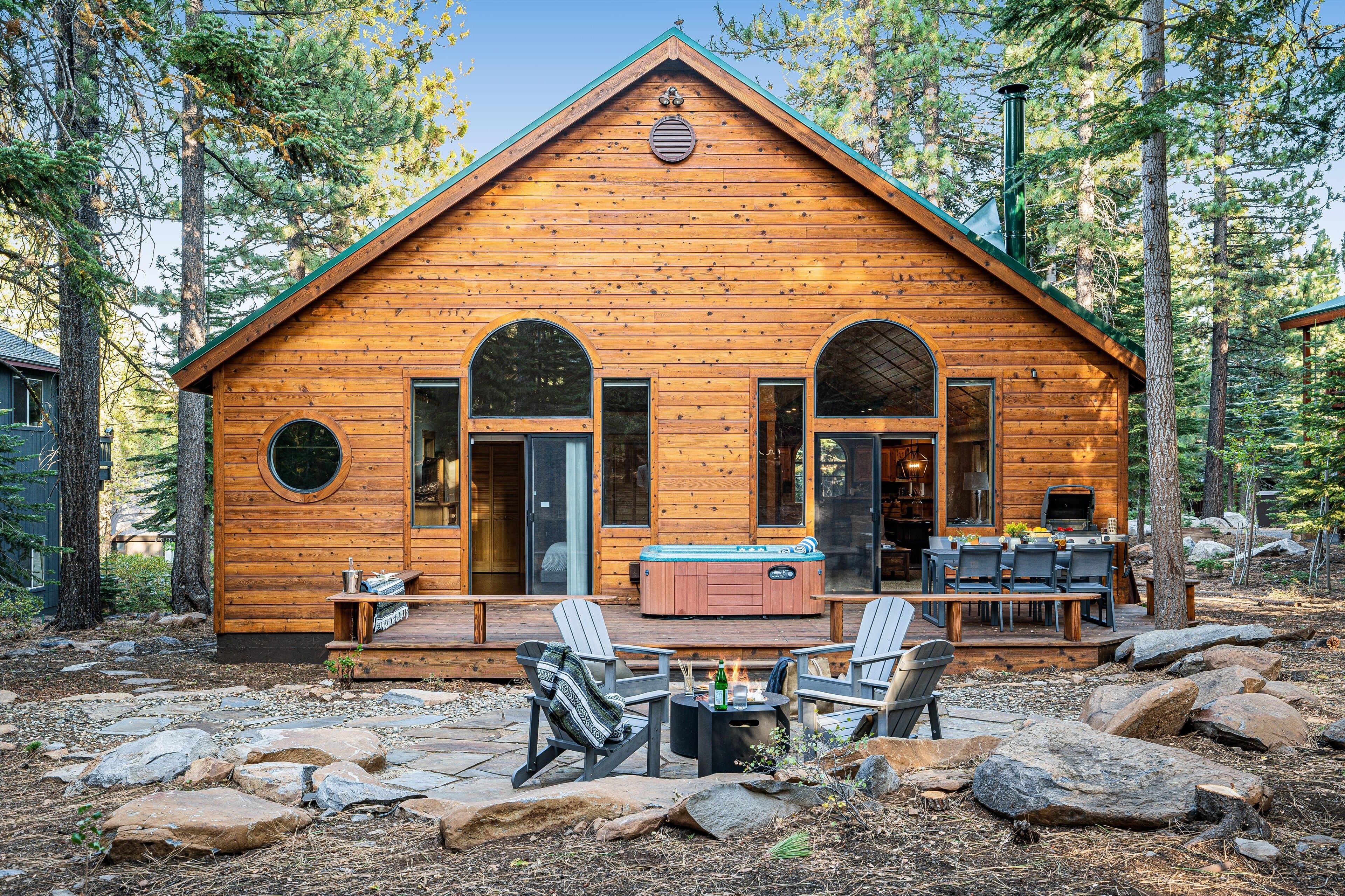 A log cabin with a deck, outdoor seating, and a hot tub.