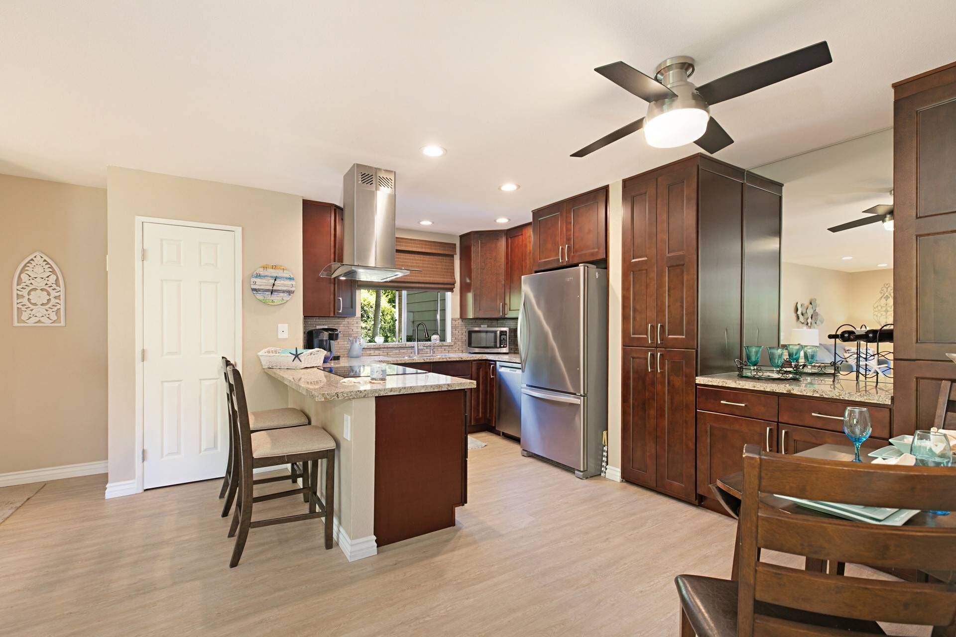 A modern kitchen with wooden cabinets, stainless steel appliances, and a ceiling fan.