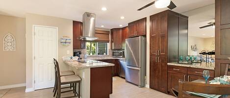A modern kitchen with wooden cabinets, stainless steel appliances, and a ceiling fan.