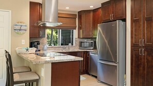 A modern kitchen with dark wood cabinets, stainless steel appliances, a granite countertop, and a built-in stove. - Walk to Strands Beach - updated, comfortable and quiet (Dana Point)