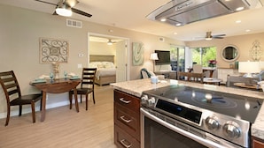 A modern kitchen with a large stove, a dining area with wooden chairs, and a bedroom visible through an open door. - Walk to Strands Beach - updated, comfortable and quiet (Dana Point)