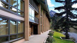 A building with large windows, a covered walkway, and a mountain in the background. - Columbine Slopeside, Ski in/out, Hot tub (Crested Butte)