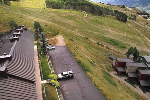 A residential area with a paved driveway, a parked vehicle, and houses with sloped roofs.