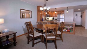 A dining area with a wooden table and chairs, a kitchen in the background, and a mirror on the wall. - Columbine Slopeside, Ski in/out, Hot tub (Crested Butte)