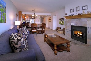 A living room with a fireplace, a dining area, and a kitchen in the background. - Columbine Slopeside, Ski in/out, Hot tub (Crested Butte)