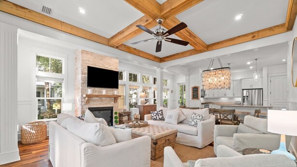 A spacious living room with a fireplace, white sofas, a coffee table, and a kitchen in the background. - Bring Fido! Stylish 4BR Home in Eastern Lake (Santa Rosa Beach)