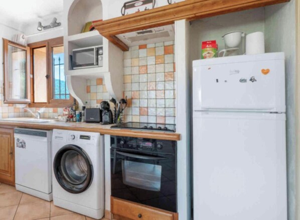 A compact kitchen with a washing machine, microwave, oven, and a refrigerator. - Holidays In Provence Alpes Maritimes (Le Bar-sur-loup)