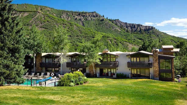 A hotel with multiple buildings, a swimming pool, and a mountainous backdrop. - Steps To Snowmass Base Village! Hot Tub, Pool & Mountain Access! Patio W/Grill, Covered Parking (Snowmass Village)