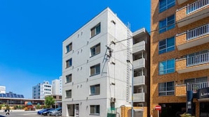 A multi-story building with a white facade and a brick building adjacent to it. - ORANGE (Sapporo)
