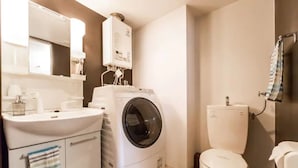 A compact bathroom with a washing machine, toilet, and a sink with a mirror above. - ORANGE (Sapporo)