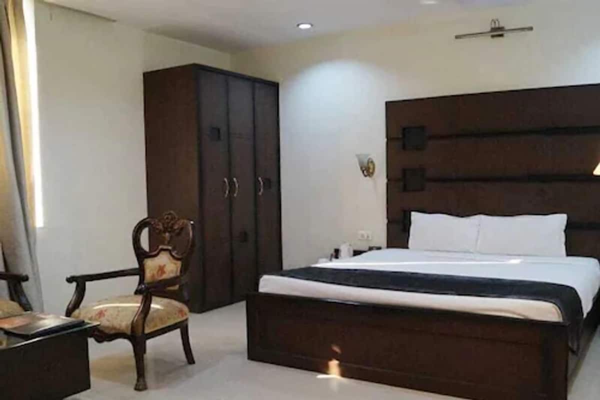 Ein Schlafzimmer mit einem großen Bett, einem Kleiderschrank, einem Sessel und einem Nachttisch.