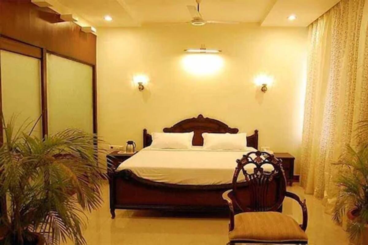 Ein Hotelzimmer mit einem großen Bett, zwei Nachttischen, einem Sessel und zwei Topfpflanzen.