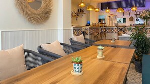 A restaurant interior with wicker furniture, pendant lighting, and a decorative mirror. - Sunny Sea View Beachfront, Wi-Fi and Air Conditioning (El Campello)