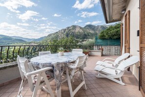 A terrace with a table and chairs, a view of mountains, and a balcony railing. - Appartamento "Le Cementine" with Lake View, Mountain View, Wi-Fi, A/C & Terrace (Vesio, Tremosine sul garda)