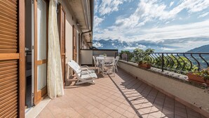 A balcony with a view of the sea, a table with chairs, and potted plants. - Appartamento "Le Cementine" with Lake View, Mountain View, Wi-Fi, A/C & Terrace (Vesio, Tremosine sul garda)