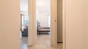 A hallway leading to a bedroom with a bed, a nightstand, and a lamp. - Appartamento "Le Cementine" with Lake View, Mountain View, Wi-Fi, A/C & Terrace (Vesio, Tremosine sul garda)