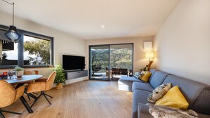 A modern living room with a dining area, a sofa, and a television.