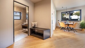 A modern kitchen with a dining area, wooden flooring, and a large window.