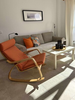 Un salon moderne avec un fauteuil à bascule, un canapé et une table basse.
